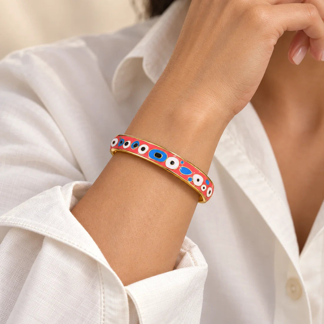 Coral Eyes stainless steel bangle in pink, blue, white with a eye motif design, worn on a model wrist