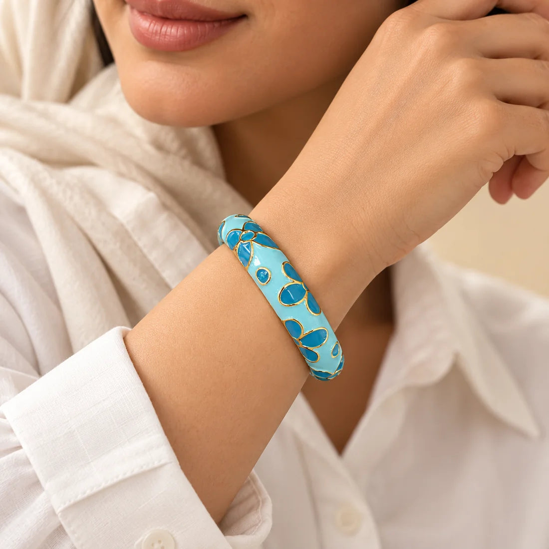 Azure Blossom stainless steel bangle in blue with a floral design, worn on a model wrist