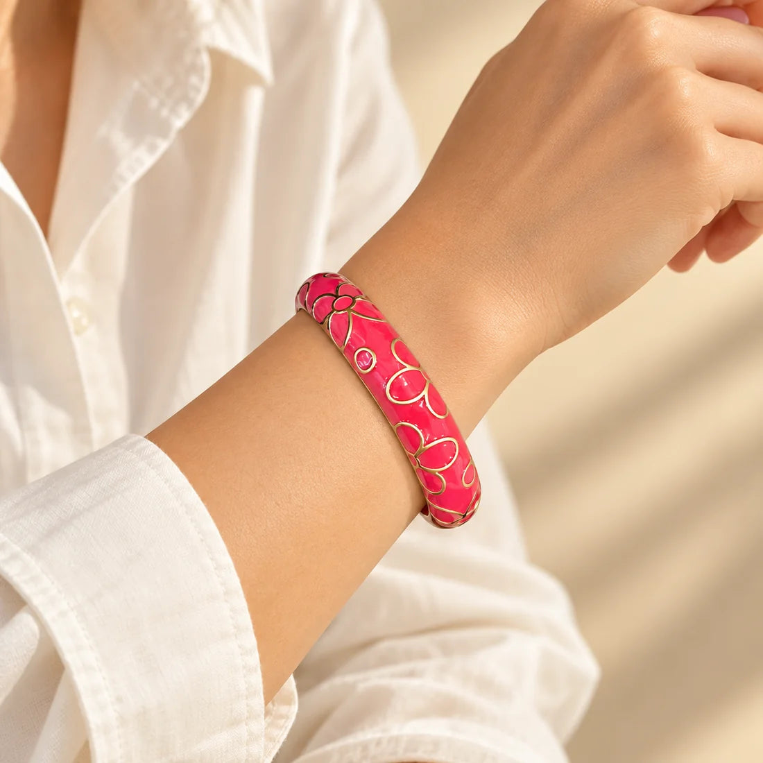 Cherry Blossom stainless steel bangle in red with a floral design, worn on a model wrist