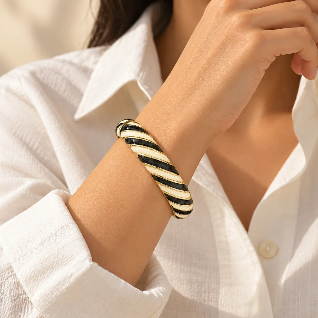 Noir Ribbons stainless steel bangle in black, white with a diagonal stripe design, worn on a model wrist