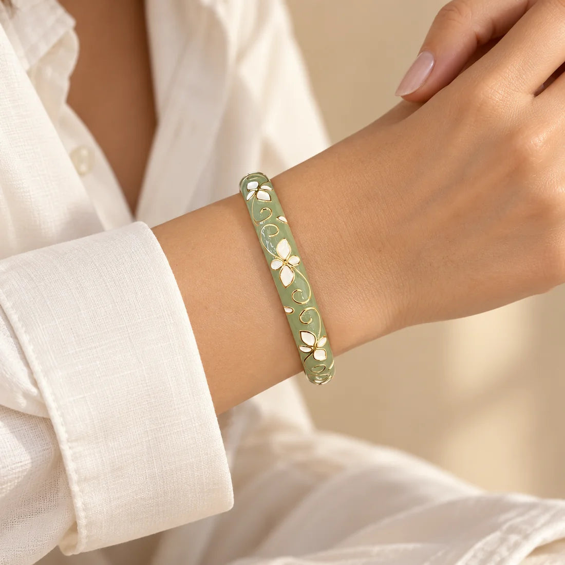 Sage Floral Scroll stainless steel bangle in green, white with a floral scroll design, worn on a model wrist