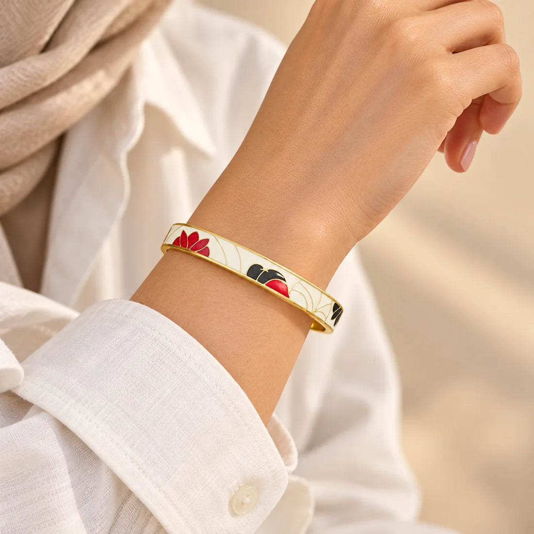 Crimson Bloom stainless steel bangle in white, red with a floral design, worn on a model wrist
