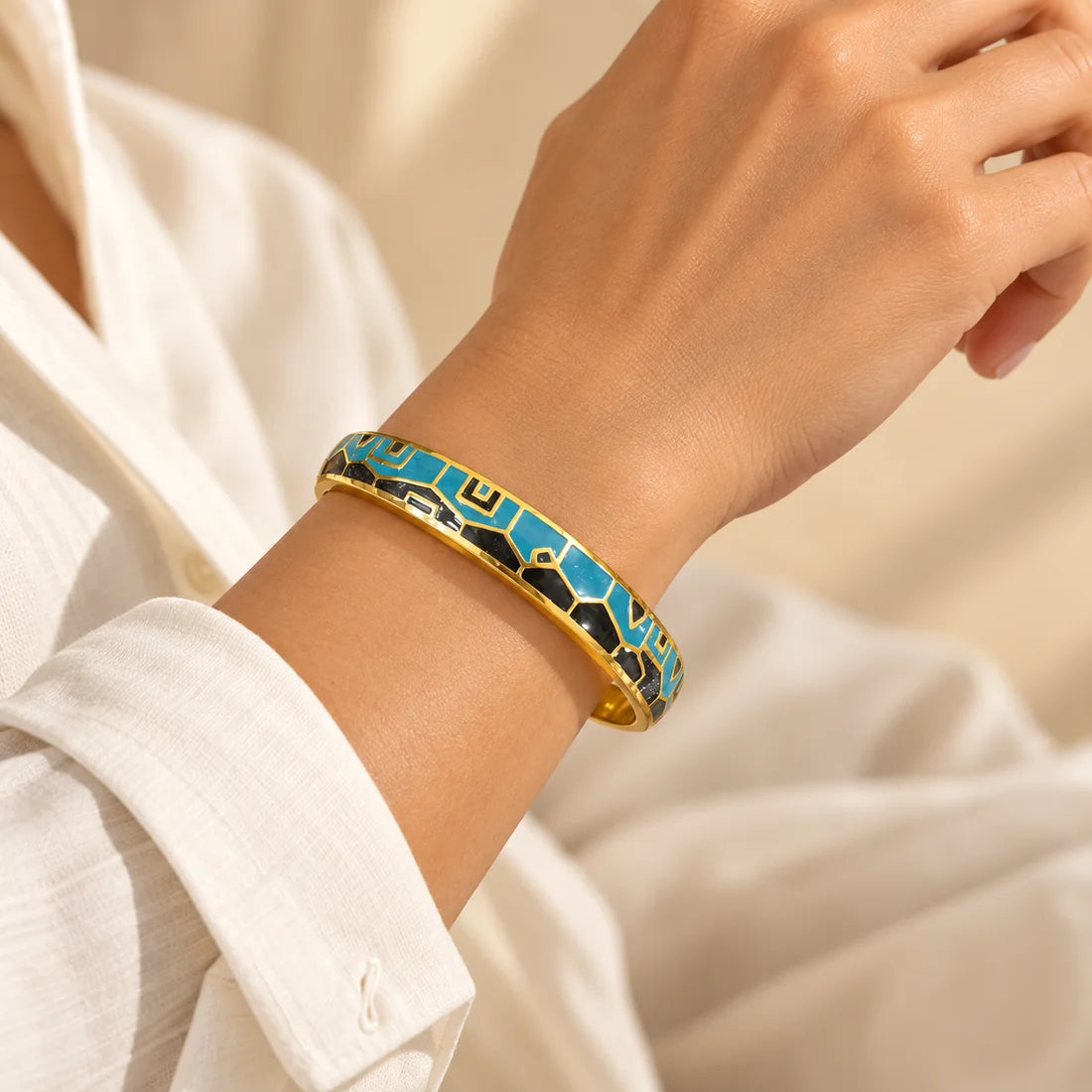 Azure Mosaic stainless steel bangle in blue, white with a geometric design, worn on a model wrist