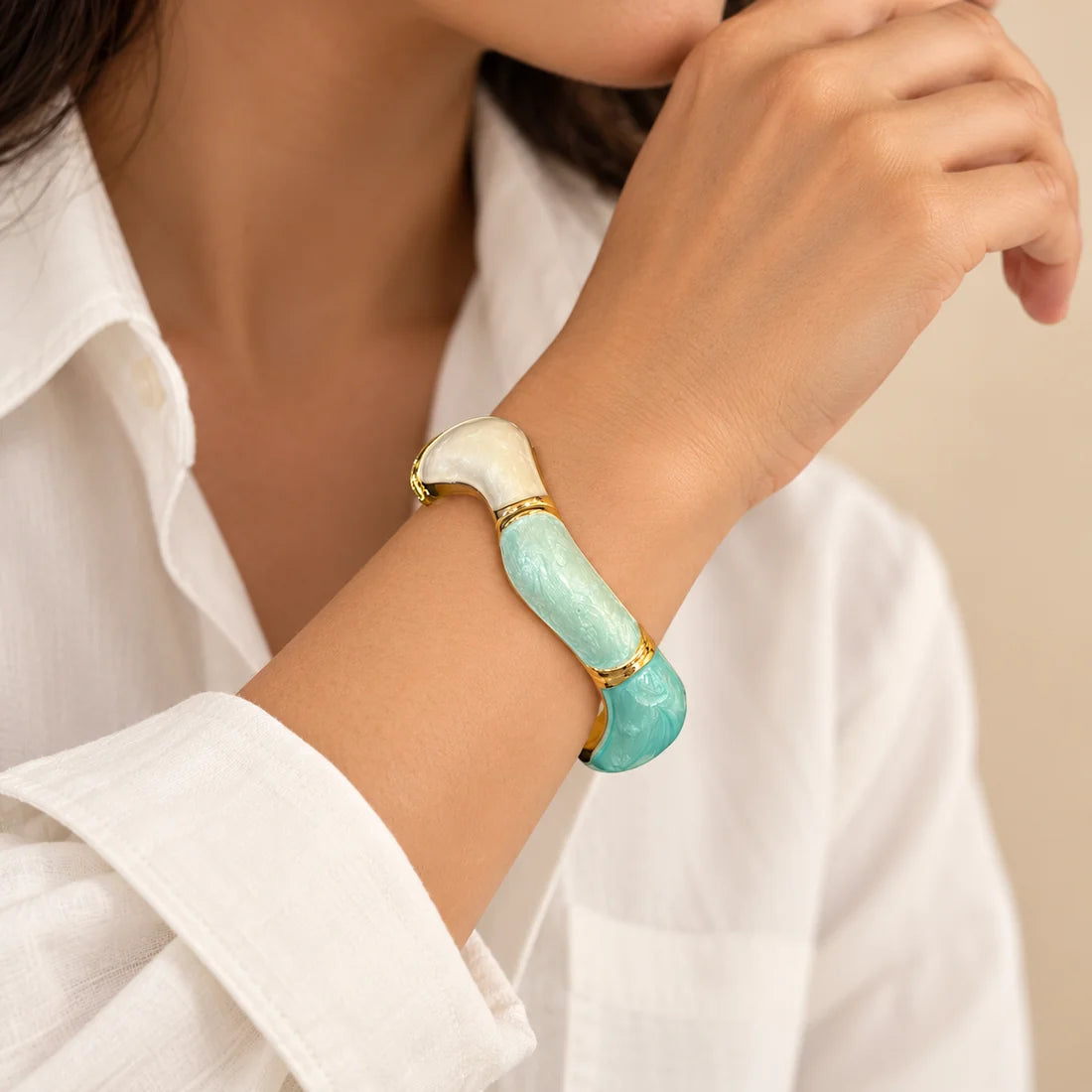 Seafoam Curve stainless steel bangle in mint, white with a colour block design, worn on a model wrist