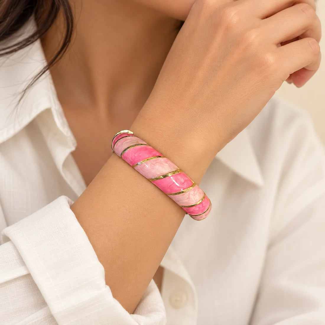 Rose Twist stainless steel bangle in pink, white with a diagonal stripe design, worn on a model wrist