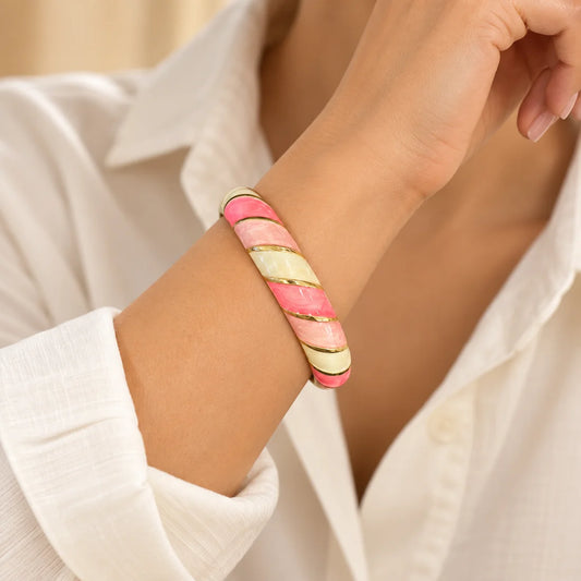 Pink Sorbet stainless steel bangle in pink, yellow, white with a diagonal stripe design, worn on a model wrist