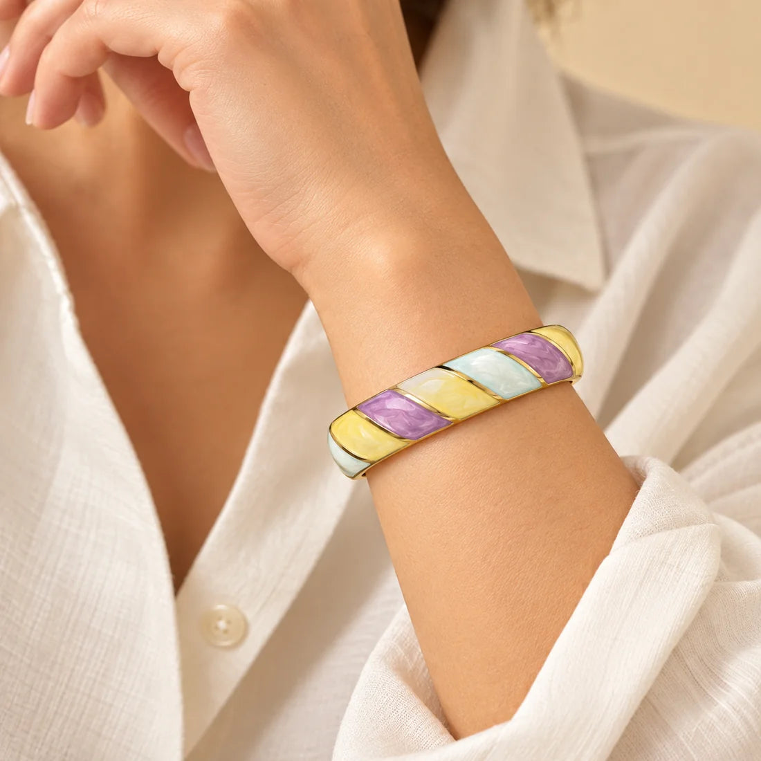 Pastel Twist stainless steel bangle in purple, yellow, white with a diagonal stripe design, worn on a model wrist