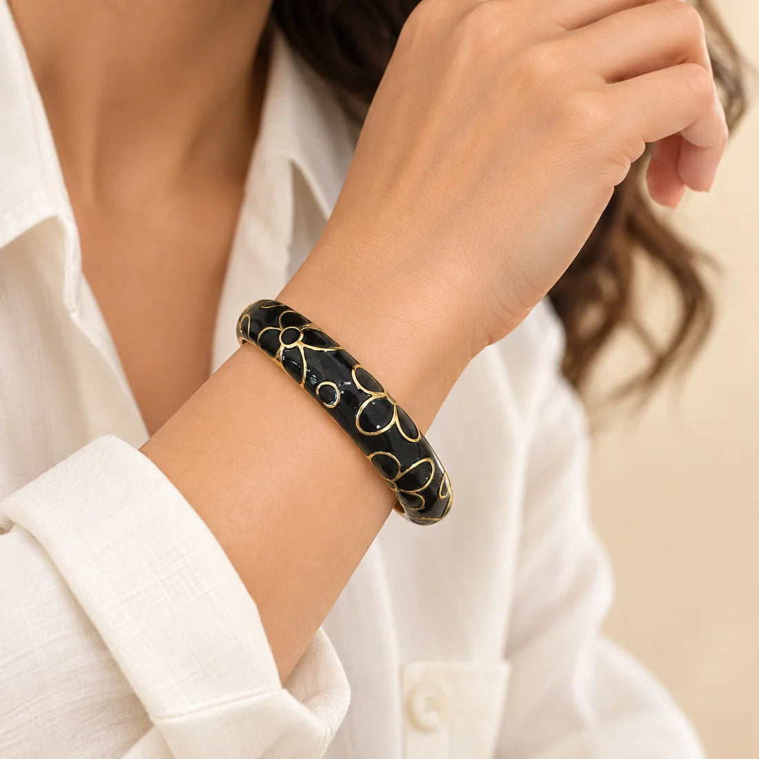 Onyx Blossom stainless steel bangle in black with a floral design, worn on a model wrist