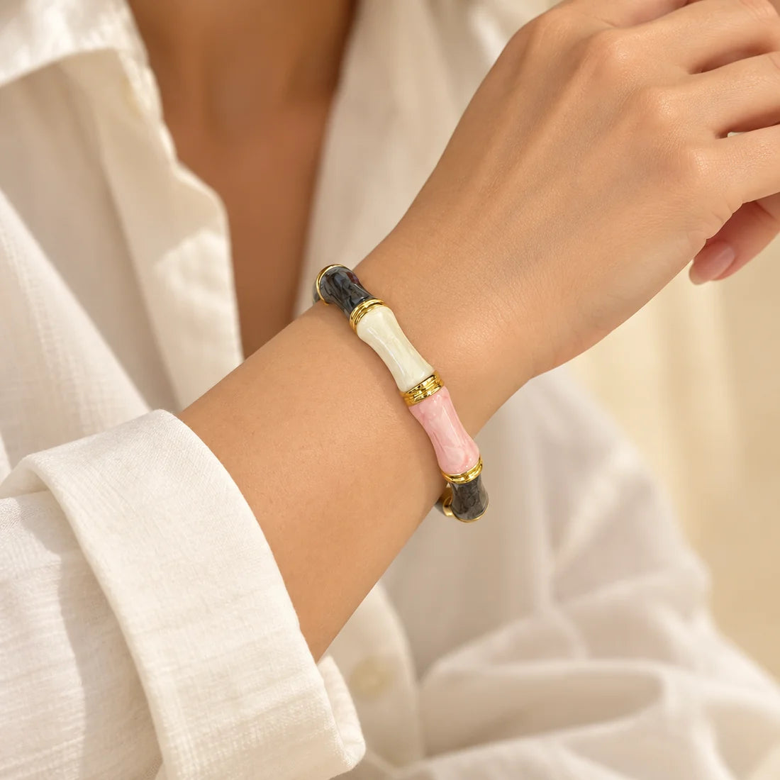 Blush Noir Bamboo stainless steel bangle in pink, black, white with a colour block design, worn on a model wrist