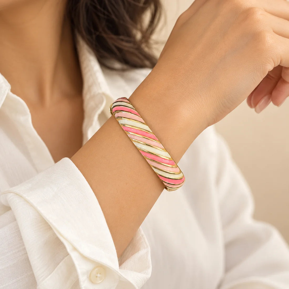 Sorbet Ribbons stainless steel bangle in pink, green, white with a diagonal stripe design, worn on a model wrist