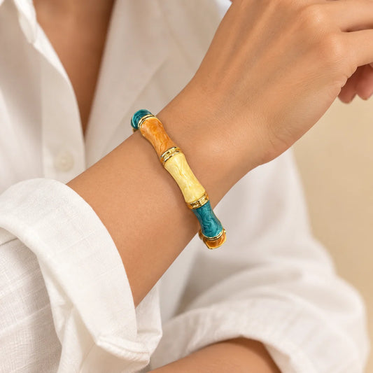 Amber Lagoon Bamboo stainless steel bangle in orange, yellow, turquoise with a colour block design, worn on a model wrist