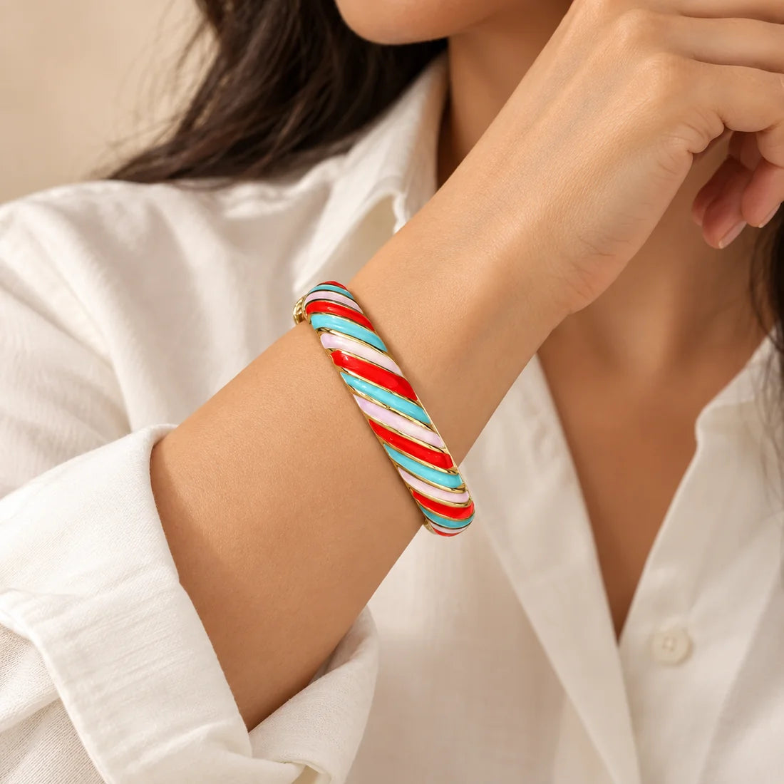 Carnival Ribbons stainless steel bangle in red, turquoise, white with a diagonal stripe design, worn on a model wrist