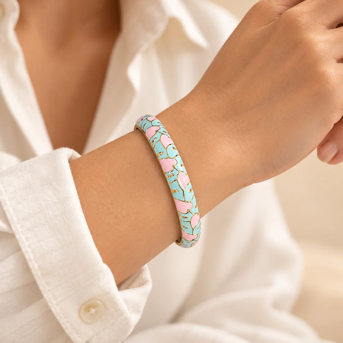 Aqua Petals stainless steel bangle in mint, pink, white with a floral design, worn on a model wrist