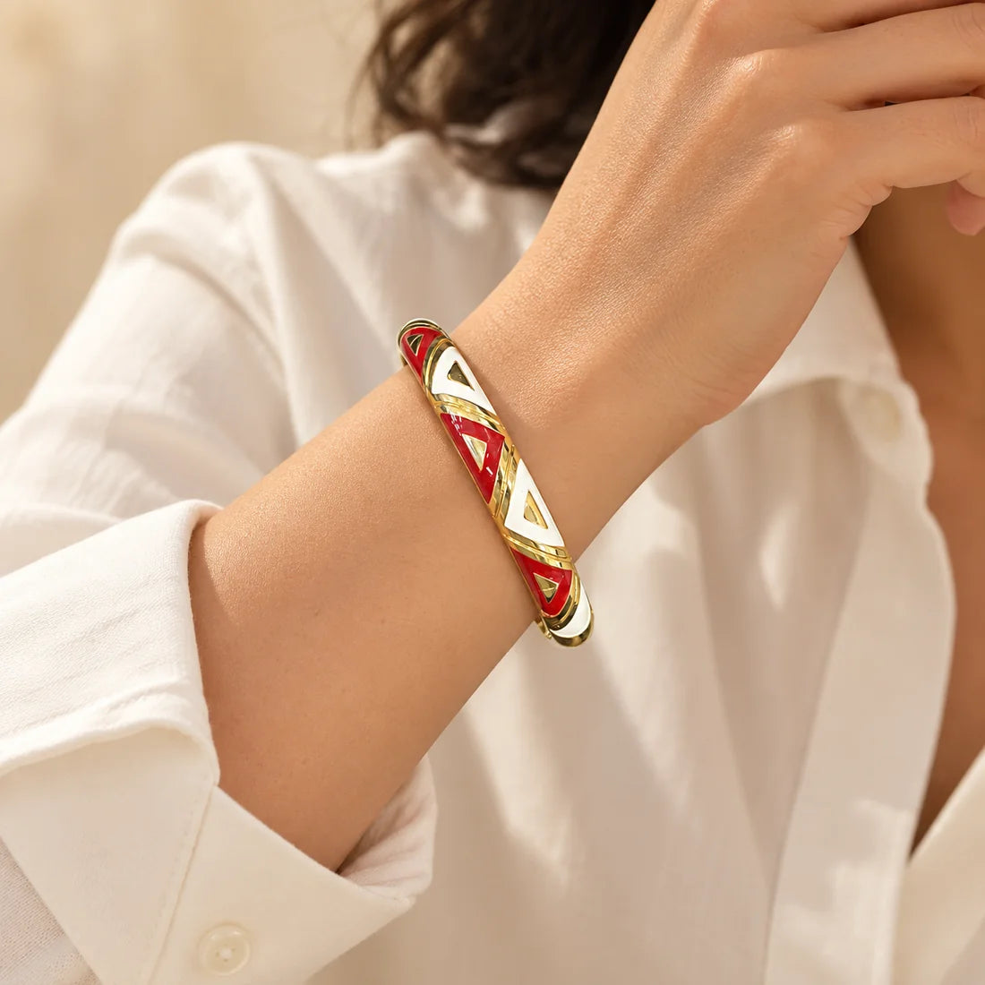 Ruby Triangles stainless steel bangle in red, white with a triangle design, worn on a model wrist