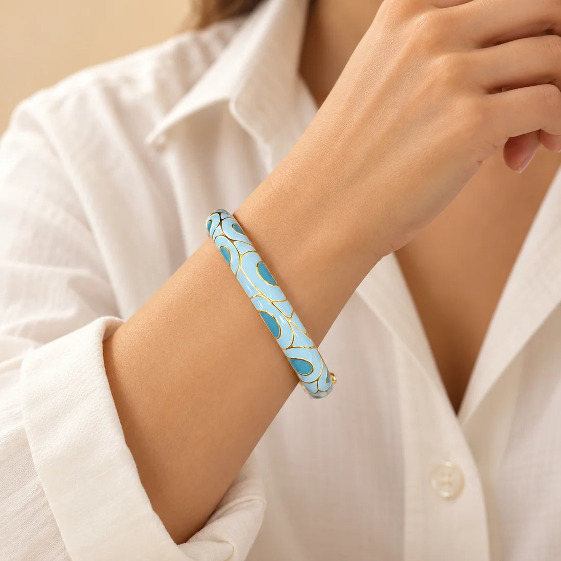 Sky Swirl stainless steel bangle in light blue, white with a swirl design, worn on a model wrist