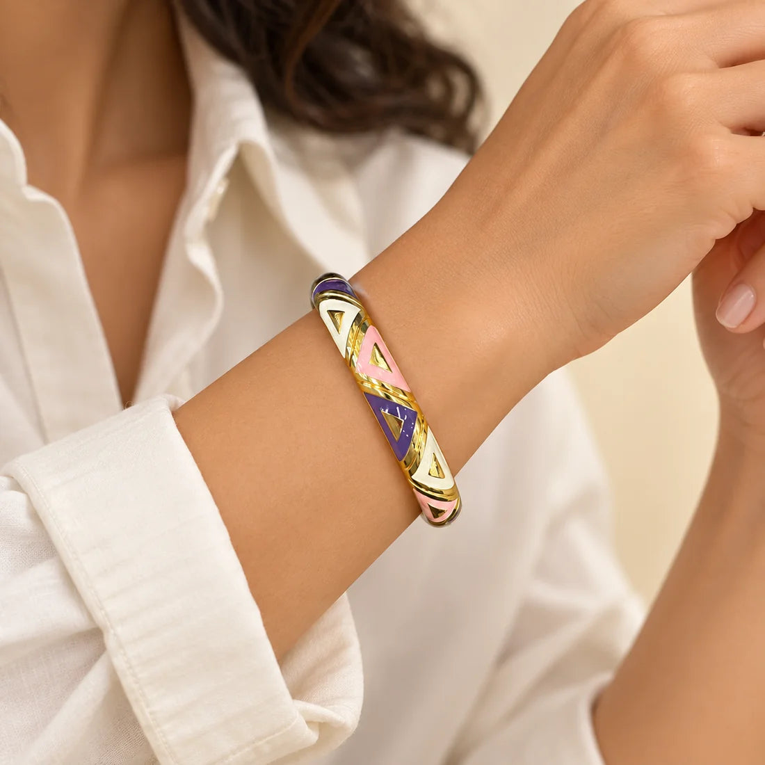 Lilac Triangles stainless steel bangle in purple, white with a triangle design, worn on a model wrist