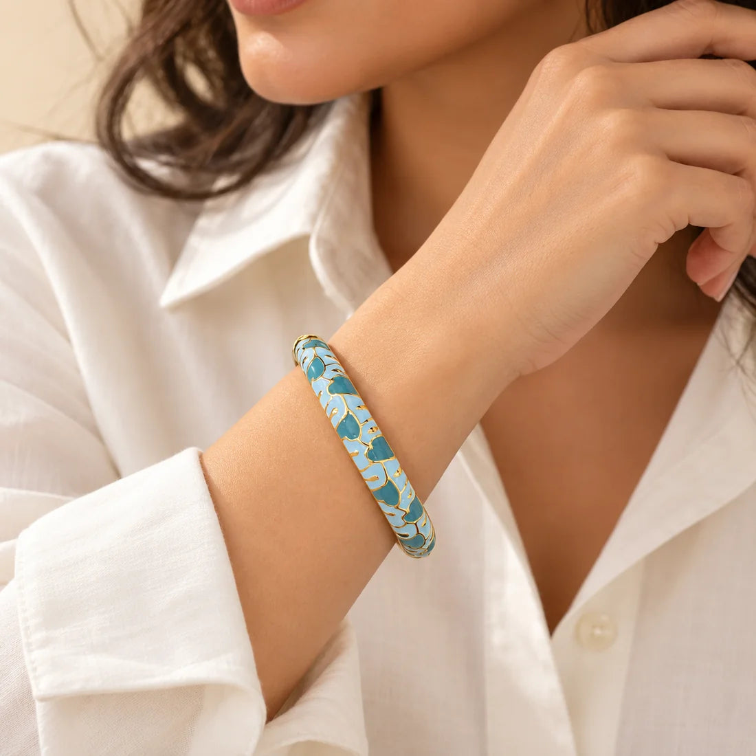 Blue Petals stainless steel bangle in blue, white with a floral design, worn on a model wrist