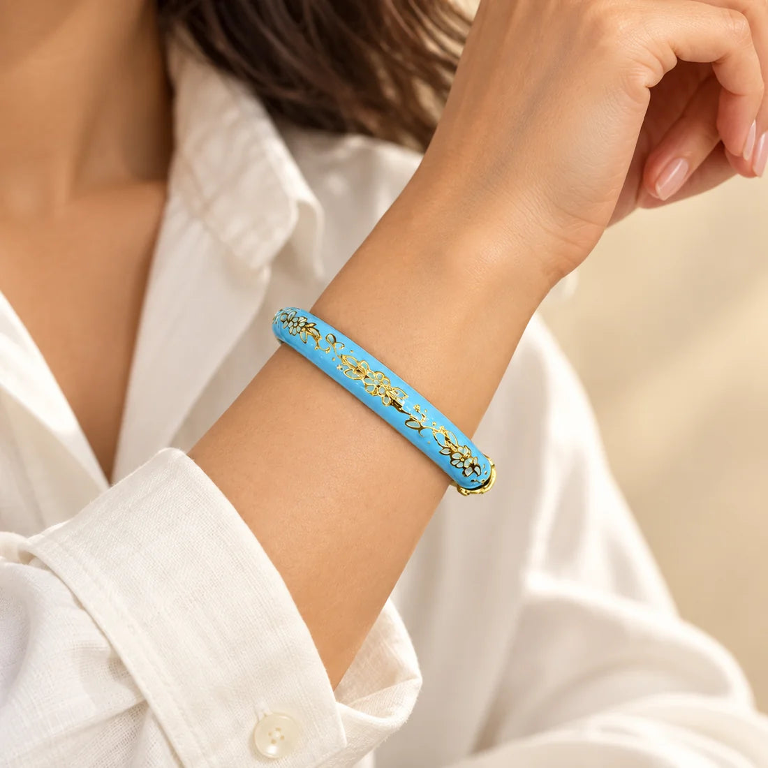 Blue Garland stainless steel bangle in blue, white with a floral design, worn on a model wrist