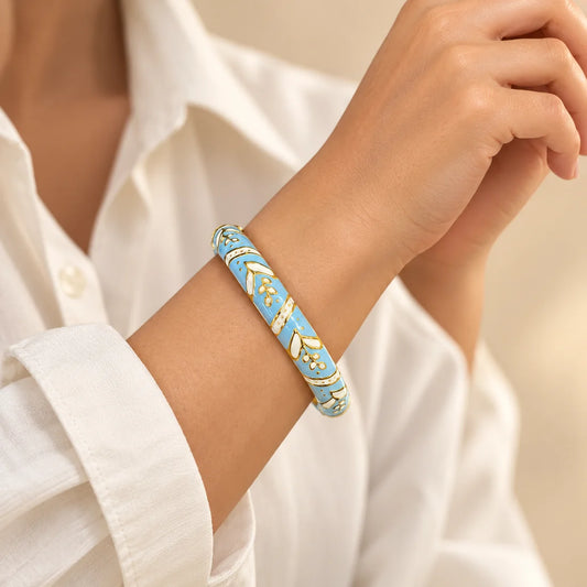 Sky Laurel - View 2 stainless steel bangle in light blue, white with a leaf design, worn on a model wrist