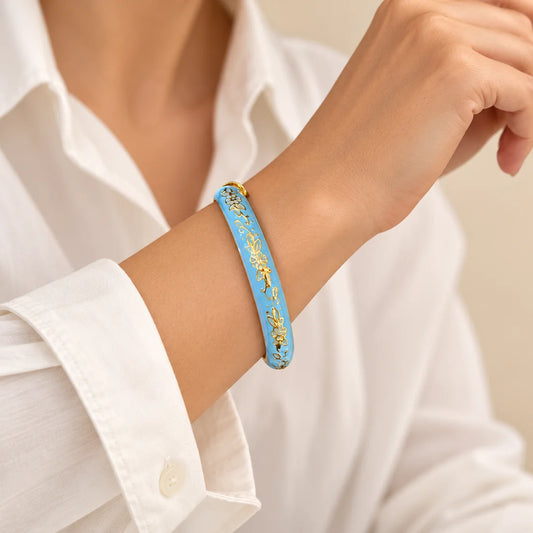 Blue Garland - View 2 stainless steel bangle in blue, white with a floral design, worn on a model wrist