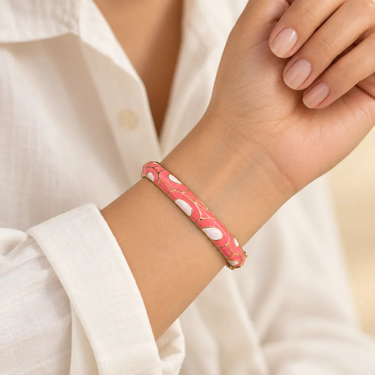 Rose Swirl stainless steel bangle in pink, white with a swirl design, worn on a model wrist