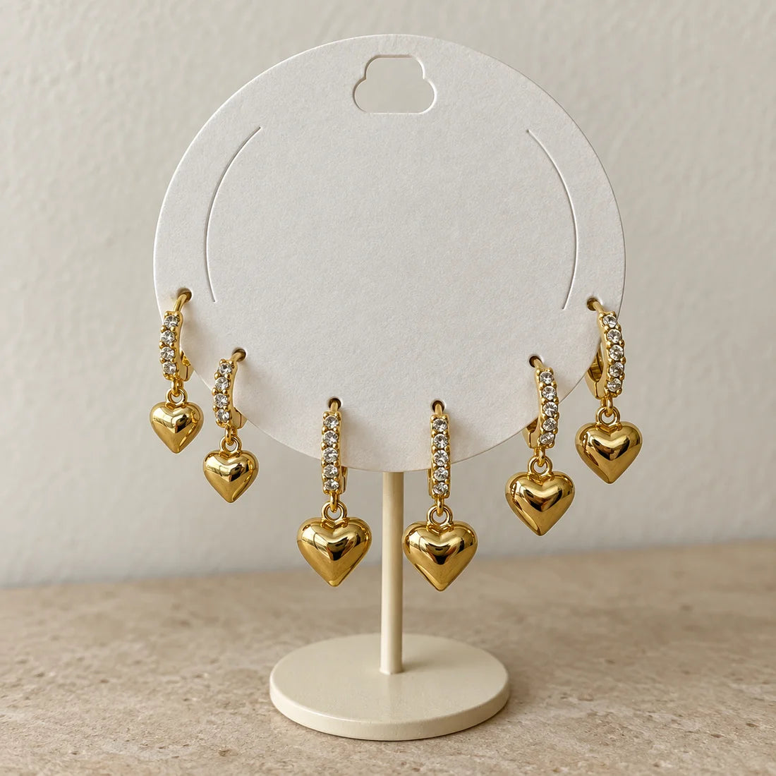 Golden Heart Hoops Set displayed on an ivory jewelry card