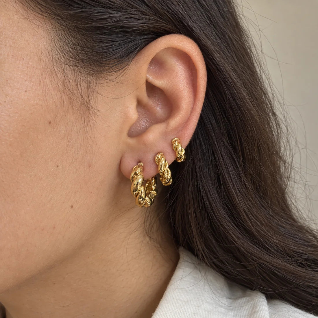 Golden Twist Hoops Set worn on an adult model ear